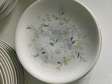 a white plate with a floral design on it next to a stack of plates