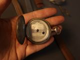 a person holding a silver pocket watch in their hand
