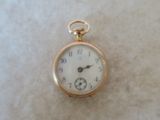 a gold pocket watch with a white face on a table