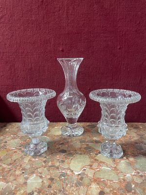 three glass vases sitting on a table with a red wall in the background