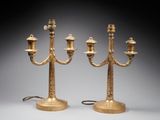 pair of brass candelabs with candles on stands