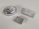 trois bijoux en argent posés sur une surface blanche