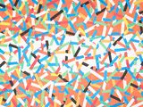 colorful sprinkles are scattered on a bright orange surface
