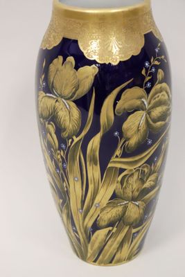 un vase bleu orné de motifs dorés sur un fond blanc