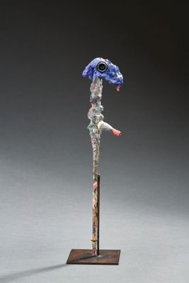 une sculpture représentant un oiseau bleu au bec rouge, posée sur un socle en bois