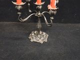 a silver candelab with three orange candles on it