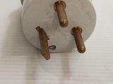 a white electrical plug with three copper plugs on it
