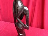 statue of a woman holding her head in her hands on a pink background