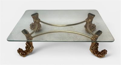 une table en verre avec un piètement en métal doré et un plateau en verre
