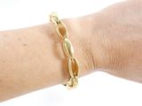 someone is wearing a gold bracelet with a twisted design on their arm