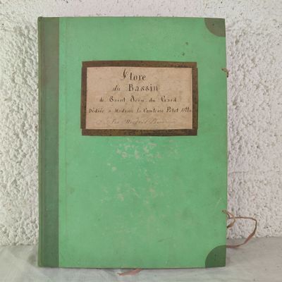 a green book sitting on a table with a white wall behind it