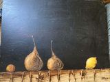 peinture représentant trois figurines et un citron sur fond noir
