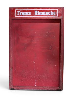 une vieille boîte rouge sur laquelle est inscrit « France Dimanche »