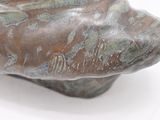 a bronze sculpture of a man ' s head on a white surface