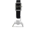 une montre noire et argentée posée sur un socle, sur fond blanc