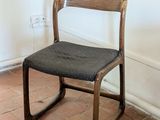 a wooden chair with a black seat on a brick floor