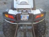 a white atv parked in a lot with a trailer in the background