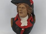 statue of a bust of a man wearing a red coat and black hat