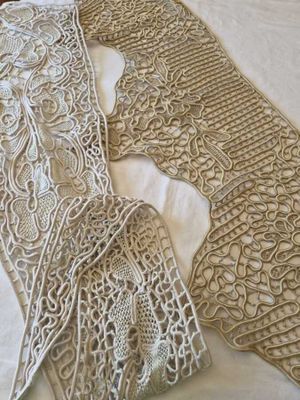 two pieces of lace on a bed next to a pillow
