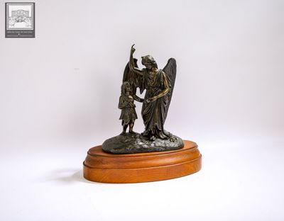 statue représentant un ange et un enfant, posée sur un socle en bois