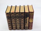 five books are lined up in a row on a white surface