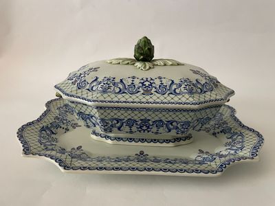 une image d'un plat bleu et blanc de type tureeny avec une feuille verte sur le dessus