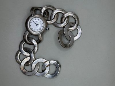 un bracelet en argent orné d'une montre, posé sur une table
