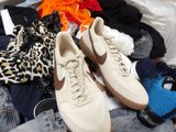 a pile of clothes and a pair of shoes on a bed