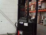 a forklift in a warehouse with shelves and pallets in the background