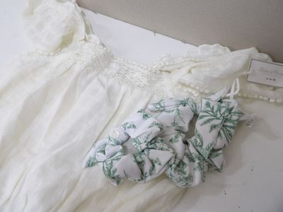 une robe blanche et une paire de mitaines posées sur un lit