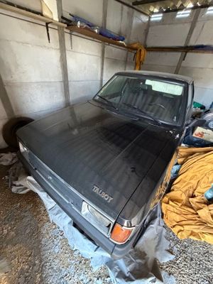 un camion noir garé dans un garage, recouvert d'une couverture jaune