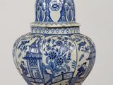 a blue and white vase with a bird on top of it