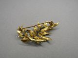 an image of a gold leaf brooch on a gray surface