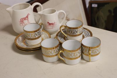 several cups and saucers are sitting on a table with a pitcher in the background