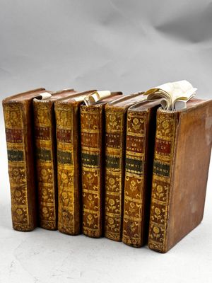 six vieux livres sont alignés sur une surface blanche