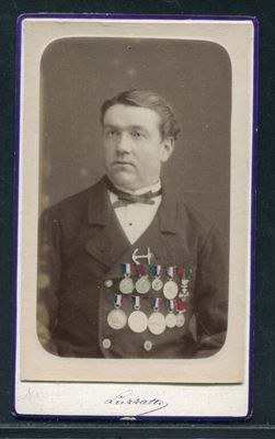 une vieille photo d'un homme en costume, avec des médailles sur la poitrine