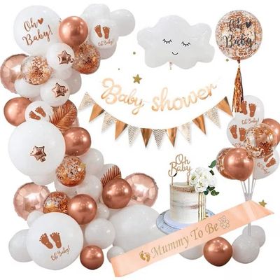 une décoration de fête prénatale dans les tons blanc et or, avec des ballons et un gâteau