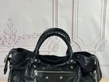 a black leather handbag sitting on top of a wooden table