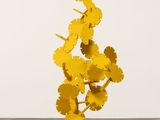 une sculpture jaune représentant des fleurs, posée sur un socle en bois