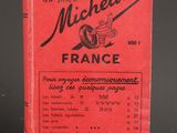 un livre rouge posé sur une table, à côté d'une table noire