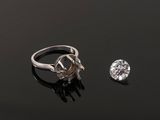 a close up of a diamond and a ring on a black surface
