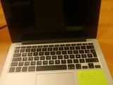 a laptop computer sitting on a desk with a sticky note on it