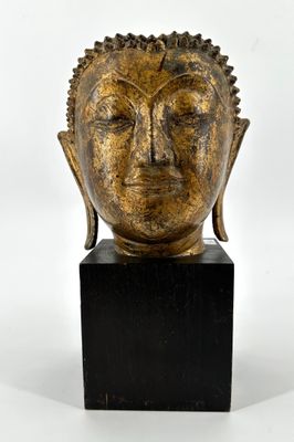 tête en bronze d'une statue de Bouddha posée sur un socle en marbre noir