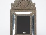 an ornate silver frame with a mirror on a white background