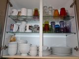 many dishes and cups on the shelves in the cabinet