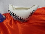 a white and black bowl sitting on a red cloth