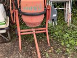 a cement mixer sitting in the yard next to a chair