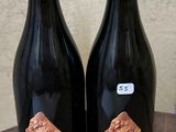 deux bouteilles de vin posées sur un tonneau en bois
