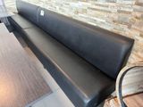 un banc en cuir noir devant un mur de briques