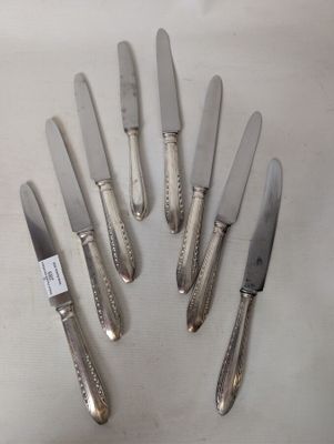 six silver plated knives are arranged in a circle on a white surface